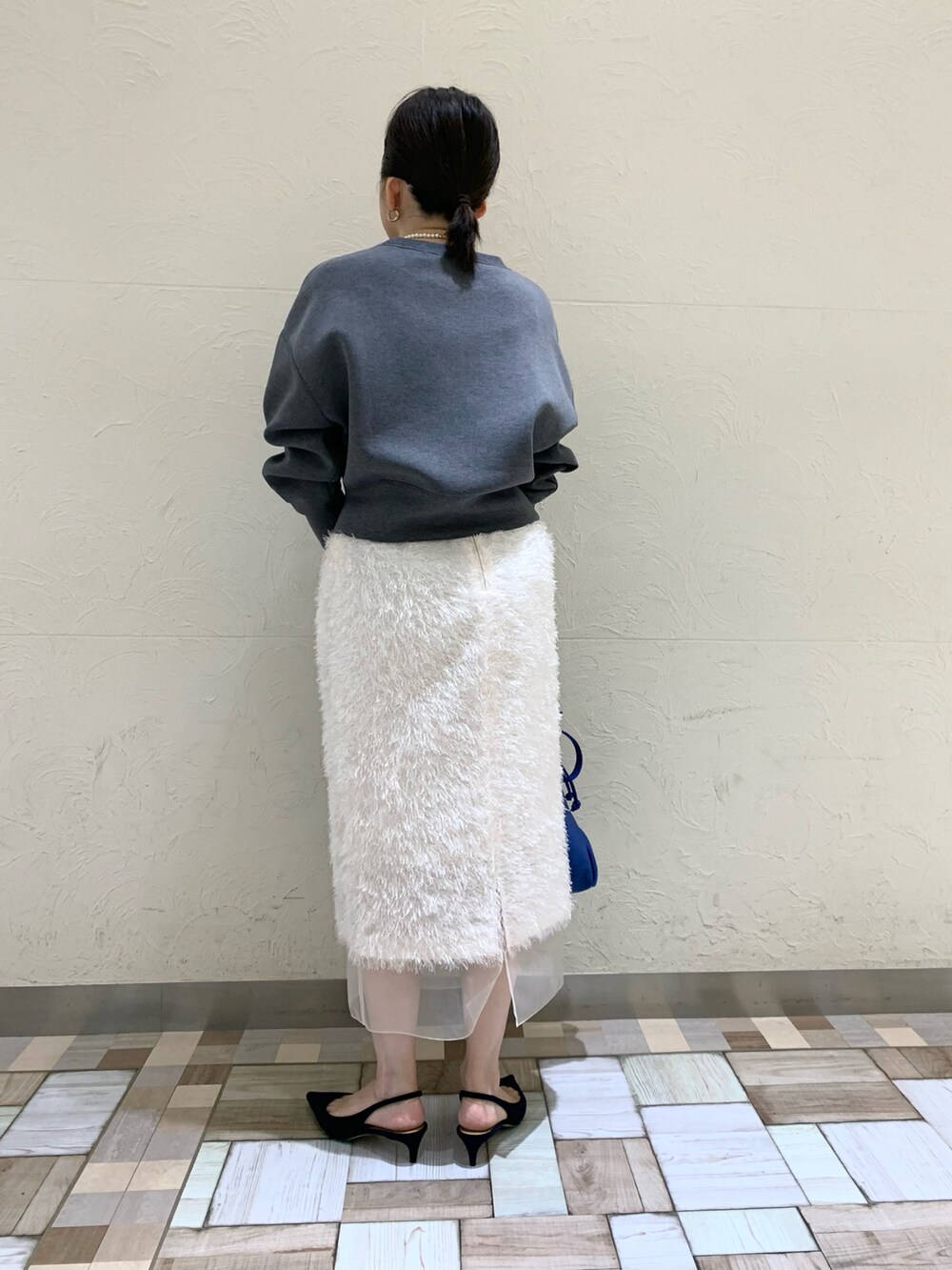 グレー系のTシャツ/カットソー、ホワイト系のスカート、ブルー系のショルダーバッグを着用したレディースの秋コーディネートの3枚目の写真