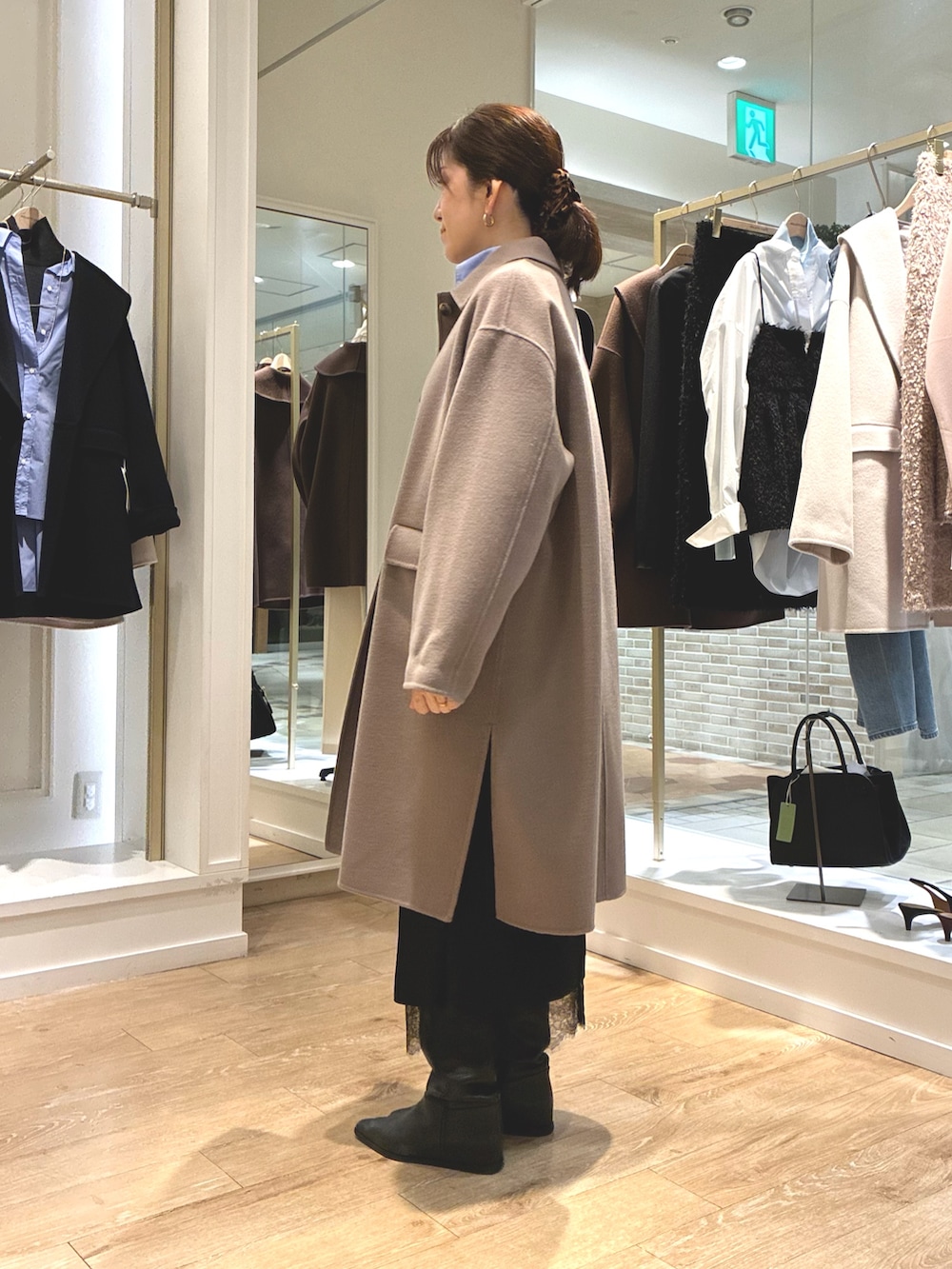 グリーン系のステンカラーコート、ブラック系のスカート、ブルー系のシャツ/ブラウスを着用したレディースの秋コーディネートの3枚目の写真