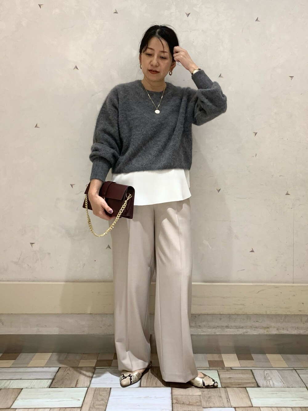 グレー系のニット/セーター、ホワイト系のタンクトップ、ベージュ系のその他パンツを着用したレディースの秋コーディネートの2枚目の写真