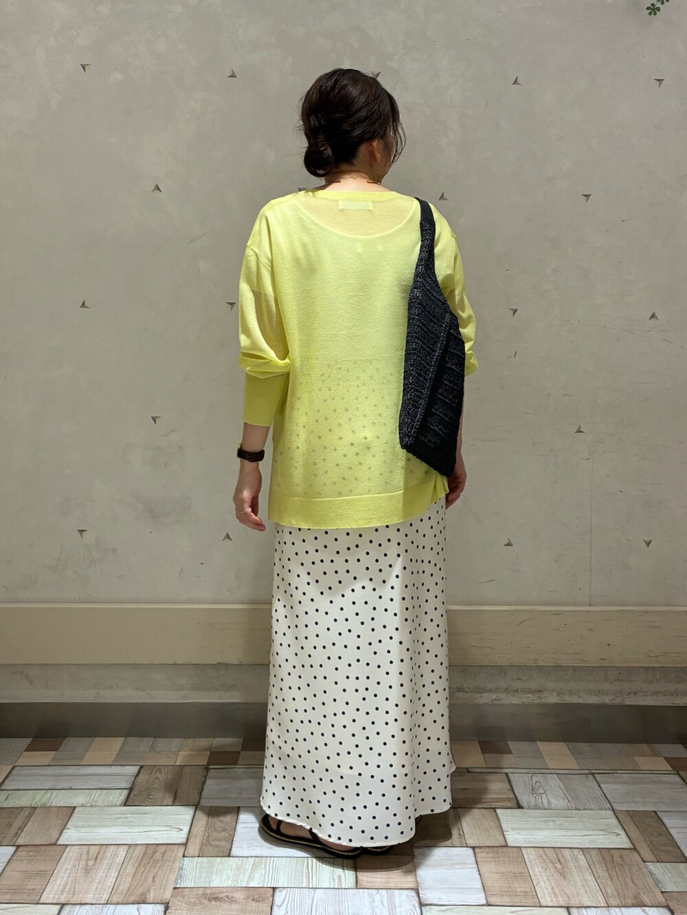 ホワイト系のスカート、イエロー系のニット/セーター、ブラック系のショルダーバッグを着用したレディースの春コーディネートの3枚目の写真