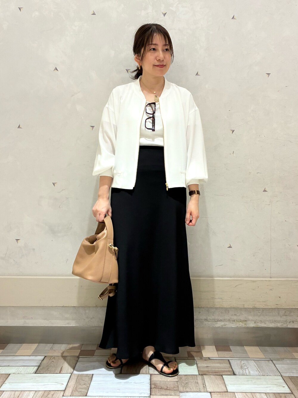 ホワイト系のブルゾン、ブラック系のスカートを着用したレディースの春コーディネートの5枚目の写真
