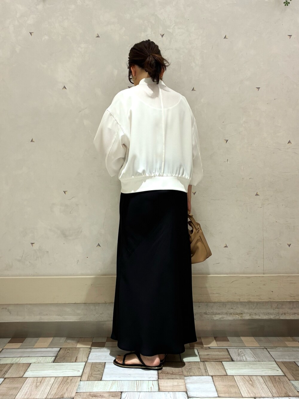 ホワイト系のブルゾン、ブラック系のスカートを着用したレディースの春コーディネートの3枚目の写真