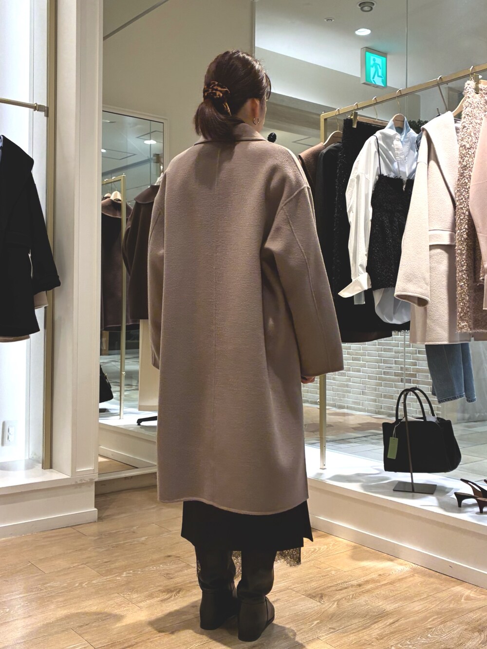 グリーン系のステンカラーコート、ブラック系のスカート、ブルー系のシャツ/ブラウスを着用したレディースの秋コーディネートの6枚目の写真