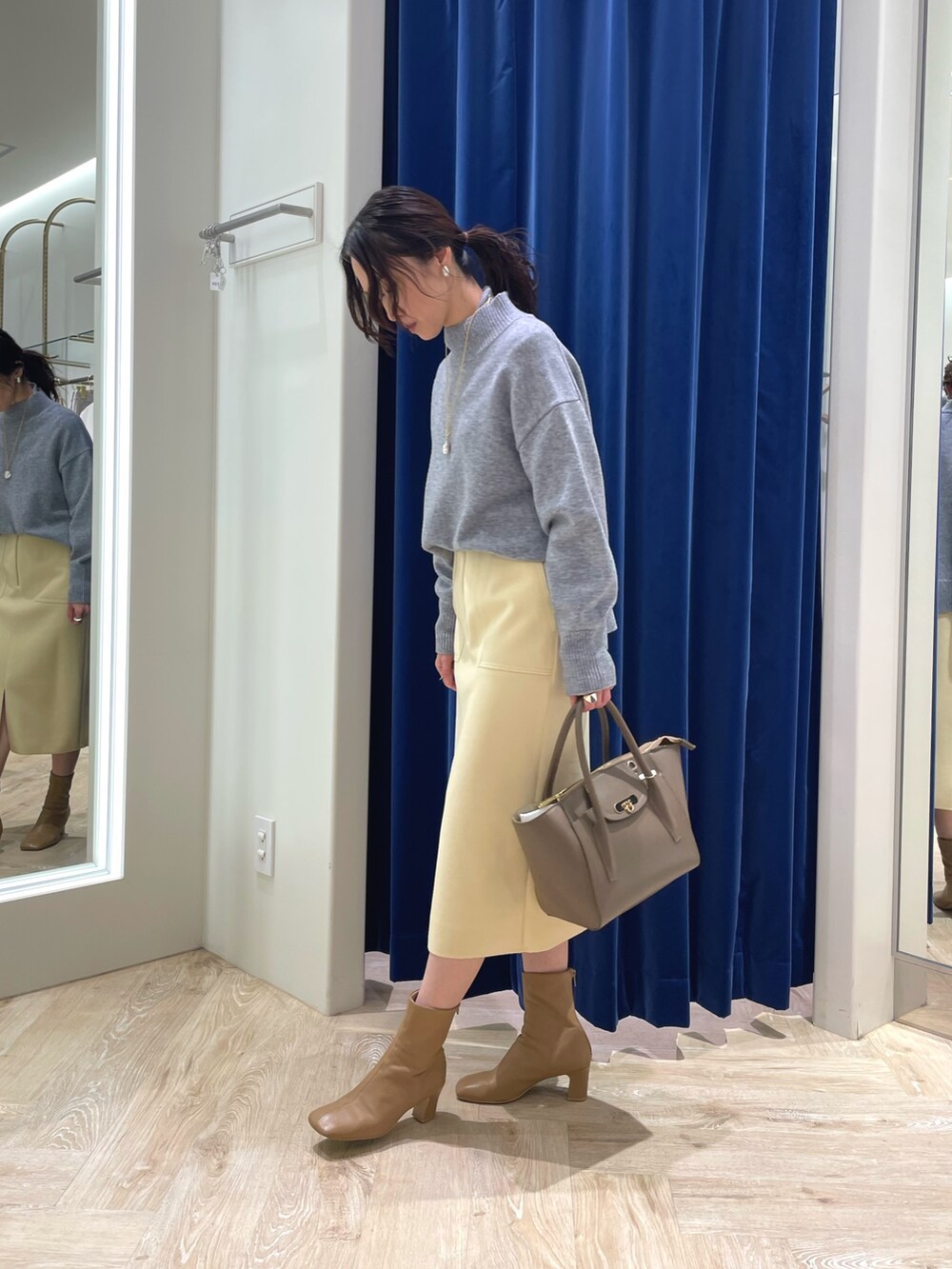 グレー系のニット/セーター、イエロー系のスカート、ブラウン系のショルダーバッグを着用したレディースの冬コーディネートの3枚目の写真