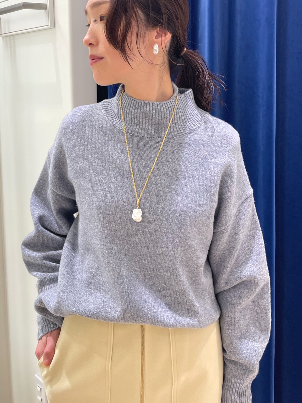 グレー系のニット/セーター、イエロー系のスカート、ブラウン系のショルダーバッグを着用したレディースの冬コーディネートの2枚目の写真