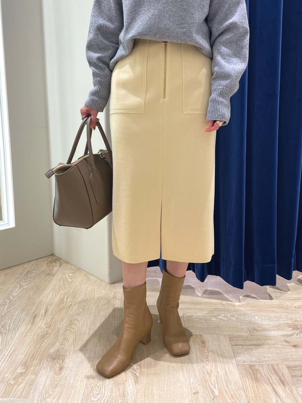 グレー系のニット/セーター、イエロー系のスカート、ブラウン系のショルダーバッグを着用したレディースの冬コーディネートの5枚目の写真