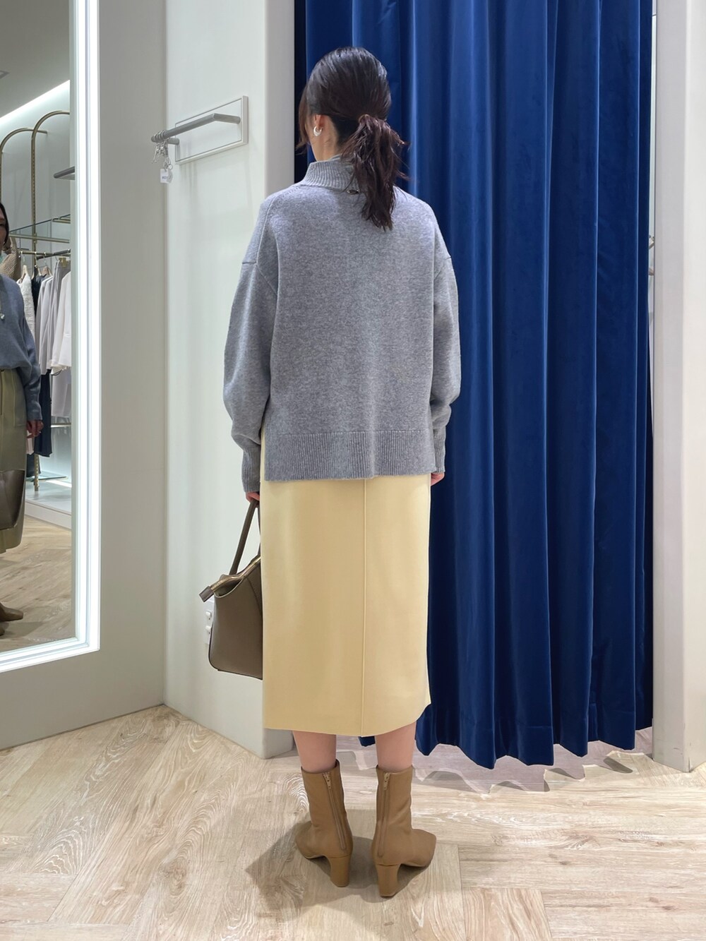 グレー系のニット/セーター、イエロー系のスカート、ブラウン系のショルダーバッグを着用したレディースの冬コーディネートの4枚目の写真