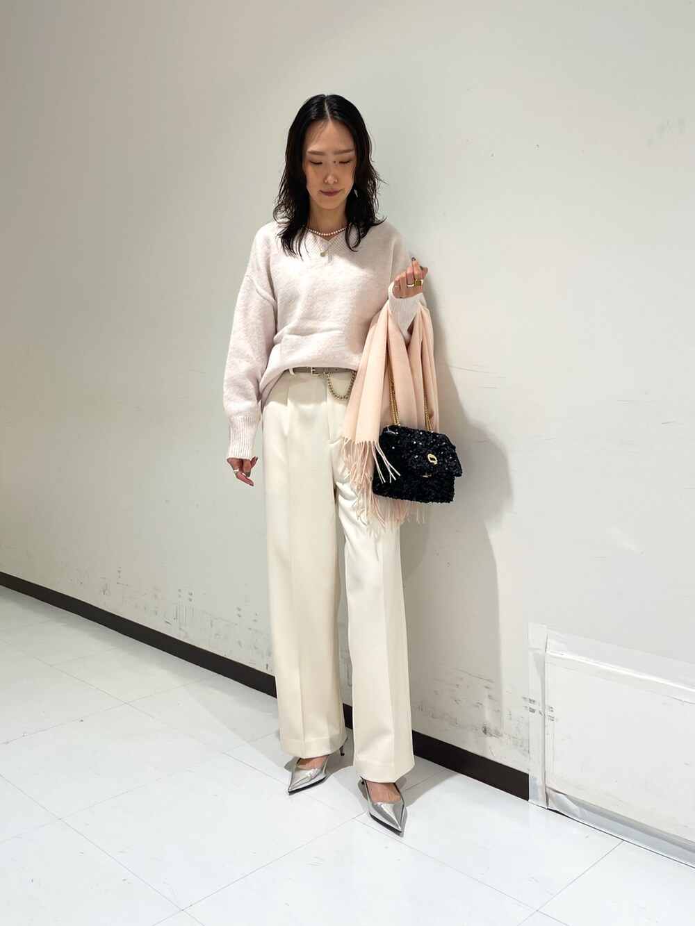 ピンク系のニット/セーター、ホワイト系のその他パンツ、ブラック系のショルダーバッグを着用したレディースの冬コーディネートの2枚目の写真