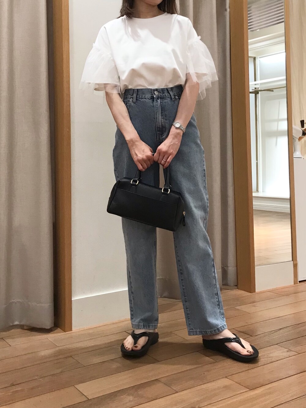 ブルー系のデニムパンツ、ブラック系のボストンバッグ、ブラック系のサンダルを着用したレディースの夏コーディネートの3枚目の写真