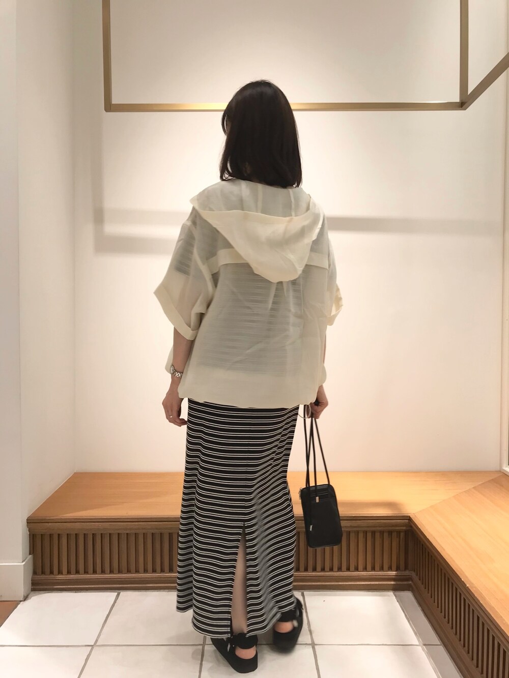 ホワイト系のブルゾン、ブラック系のワンピース、ブラック系のショルダーバッグを着用したレディースの夏コーディネートの2枚目の写真