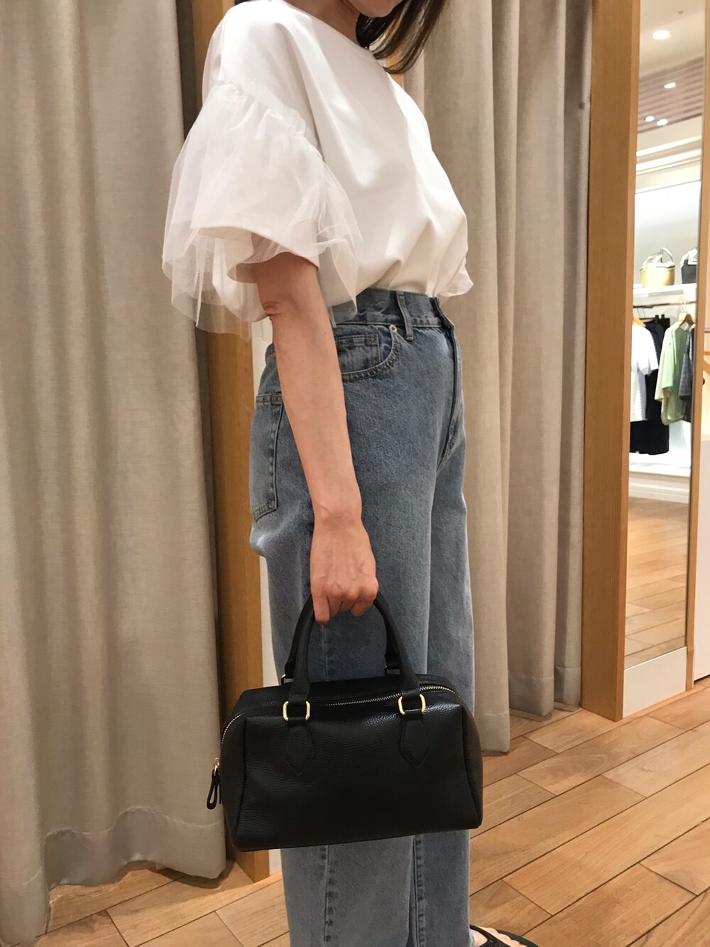 ブルー系のデニムパンツ、ブラック系のボストンバッグ、ブラック系のサンダルを着用したレディースの夏コーディネートの4枚目の写真