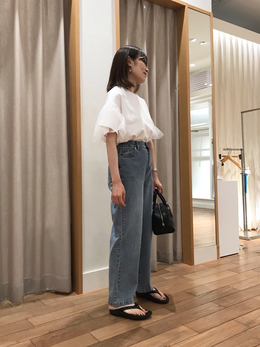 ブルー系のデニムパンツ、ブラック系のボストンバッグ、ブラック系のサンダルを着用したレディースの夏コーディネートの2枚目の写真