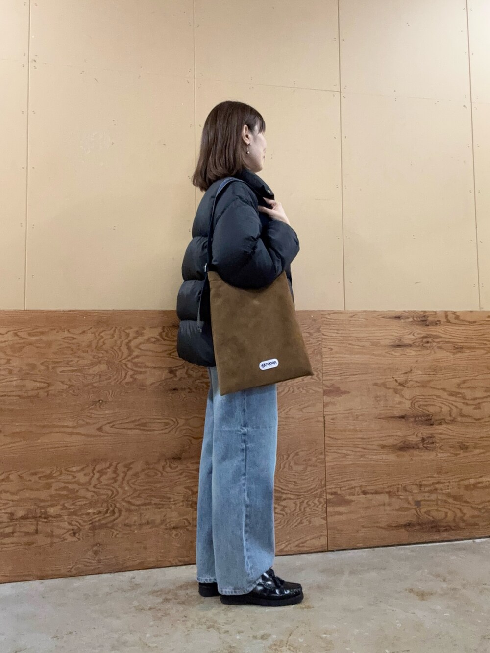 イエロー系のショルダーバッグ、ブルー系のデニムパンツ、ブラック系のダウンジャケット/コートを着用したレディースの秋コーディネートの2枚目の写真
