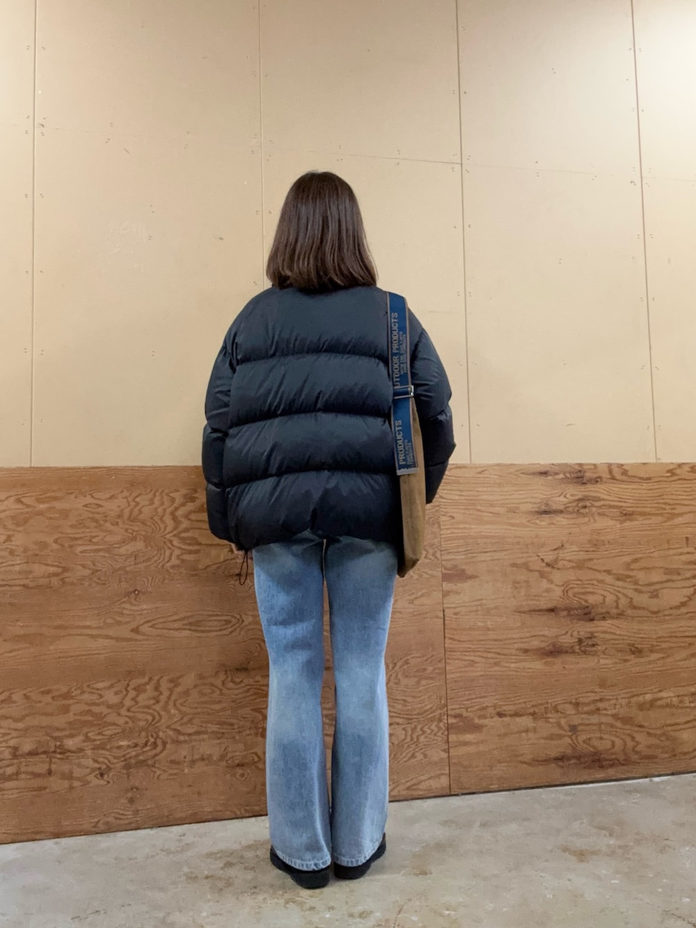 イエロー系のショルダーバッグ、ブルー系のデニムパンツ、ブラック系のダウンジャケット/コートを着用したレディースの秋コーディネートの3枚目の写真