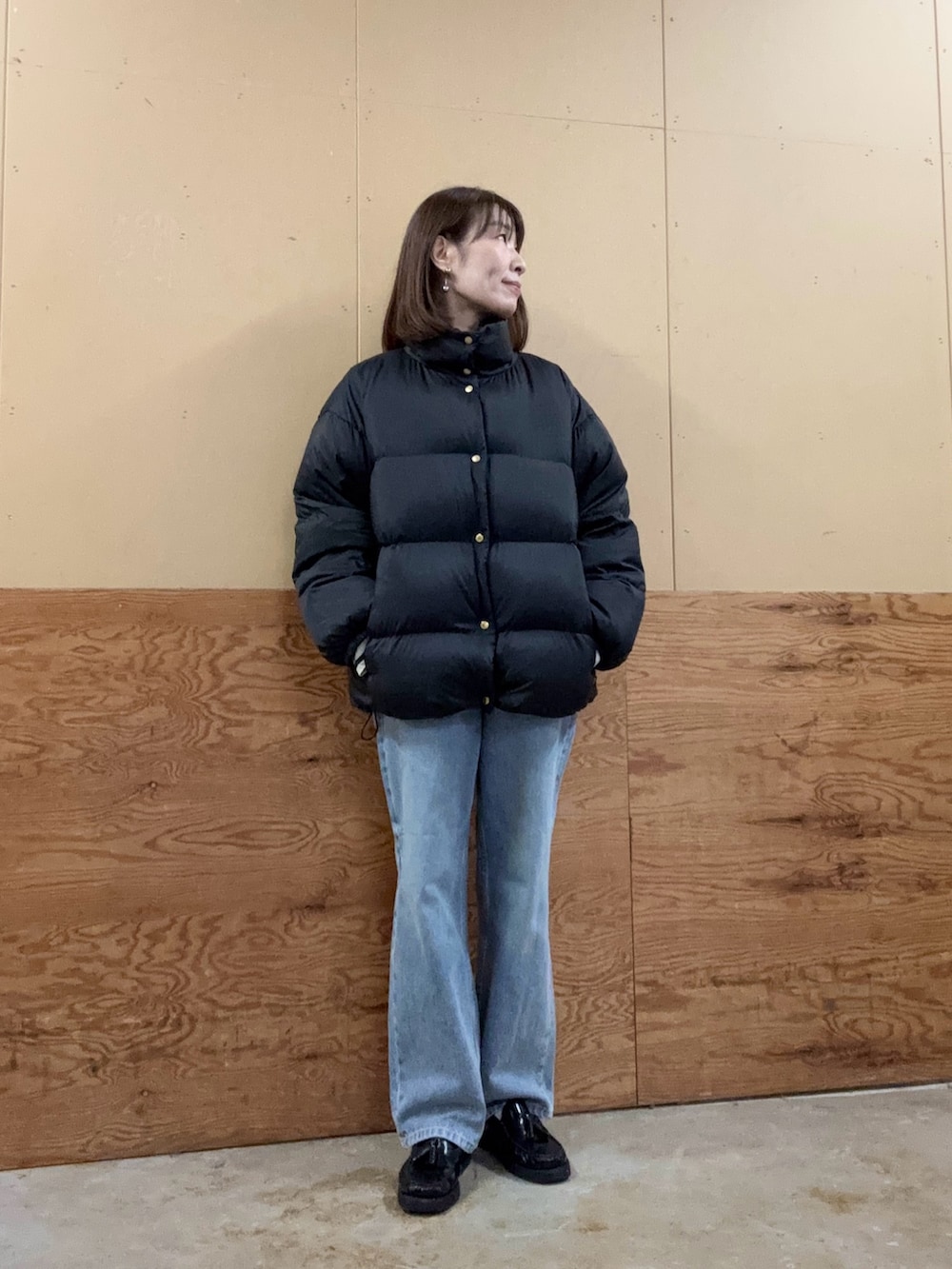 イエロー系のショルダーバッグ、ブルー系のデニムパンツ、ブラック系のダウンジャケット/コートを着用したレディースの秋コーディネートの4枚目の写真