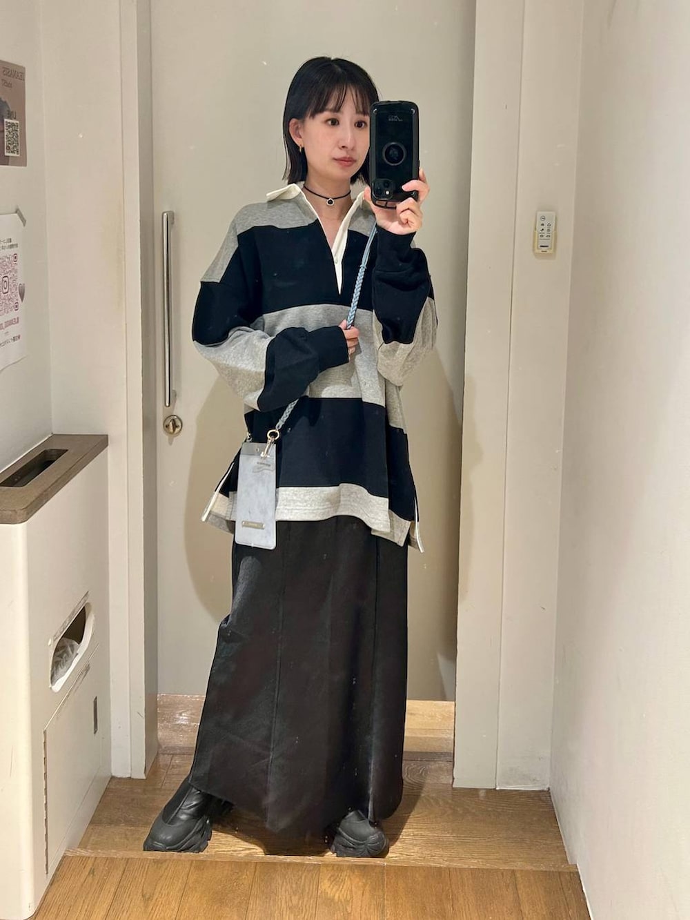 ブラック系のブーツ、グレー系のポロシャツ、ブラック系のスカートを着用したレディースの冬コーディネートの3枚目の写真