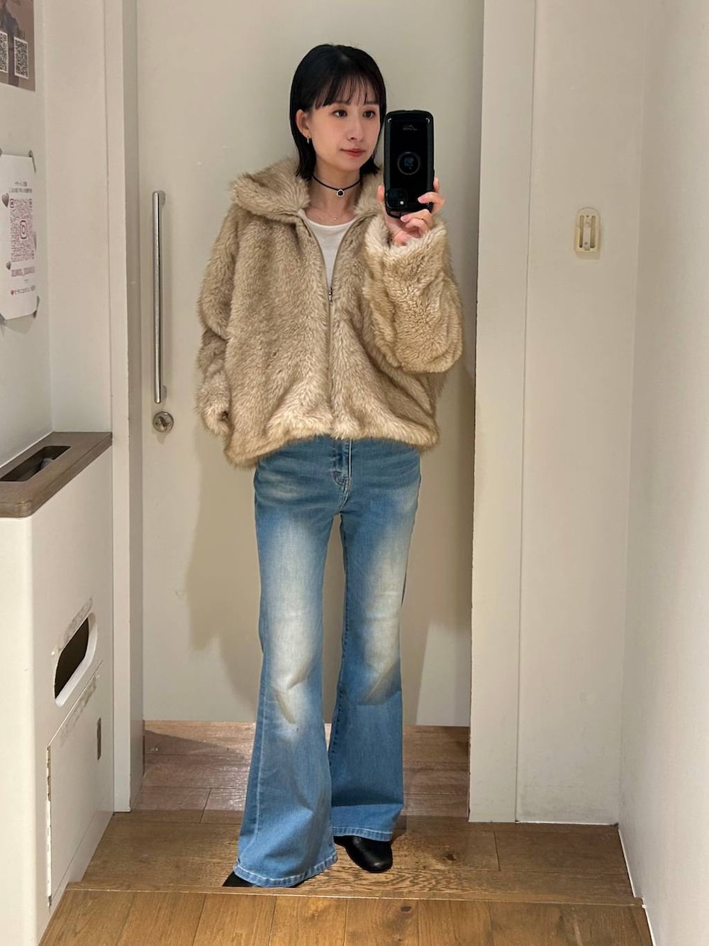 ベージュ系のブルゾン、ブルー系のデニムパンツ、ブラック系のチョーカーを着用したレディースの冬コーディネートの3枚目の写真