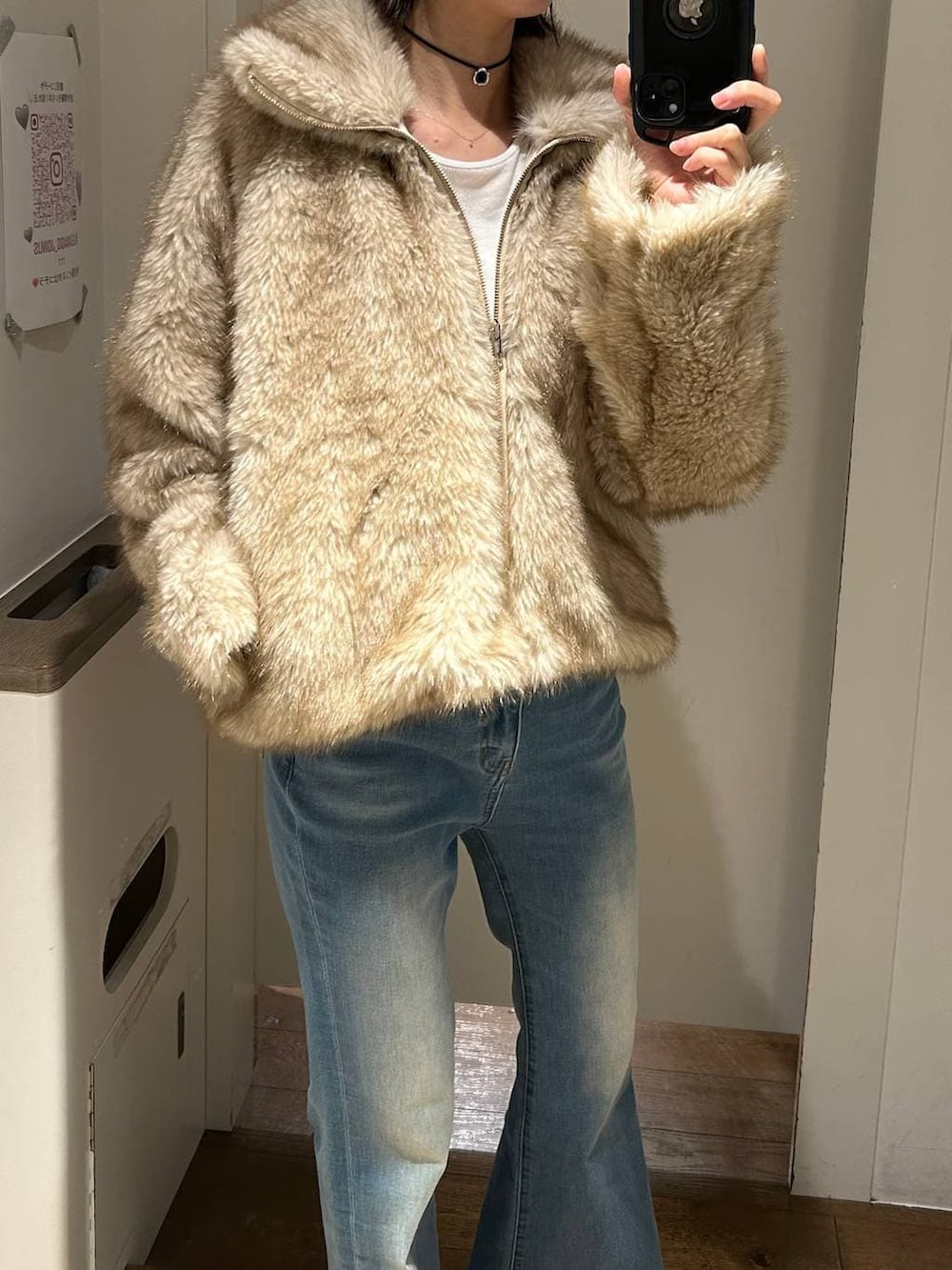 ベージュ系のブルゾン、ブルー系のデニムパンツ、ブラック系のチョーカーを着用したレディースの冬コーディネートの2枚目の写真