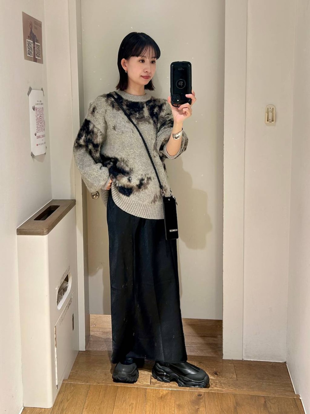 グレー系のニット/セーター、ブラック系のブーツ、ブラック系のスカートを着用したレディースの秋コーディネートの2枚目の写真