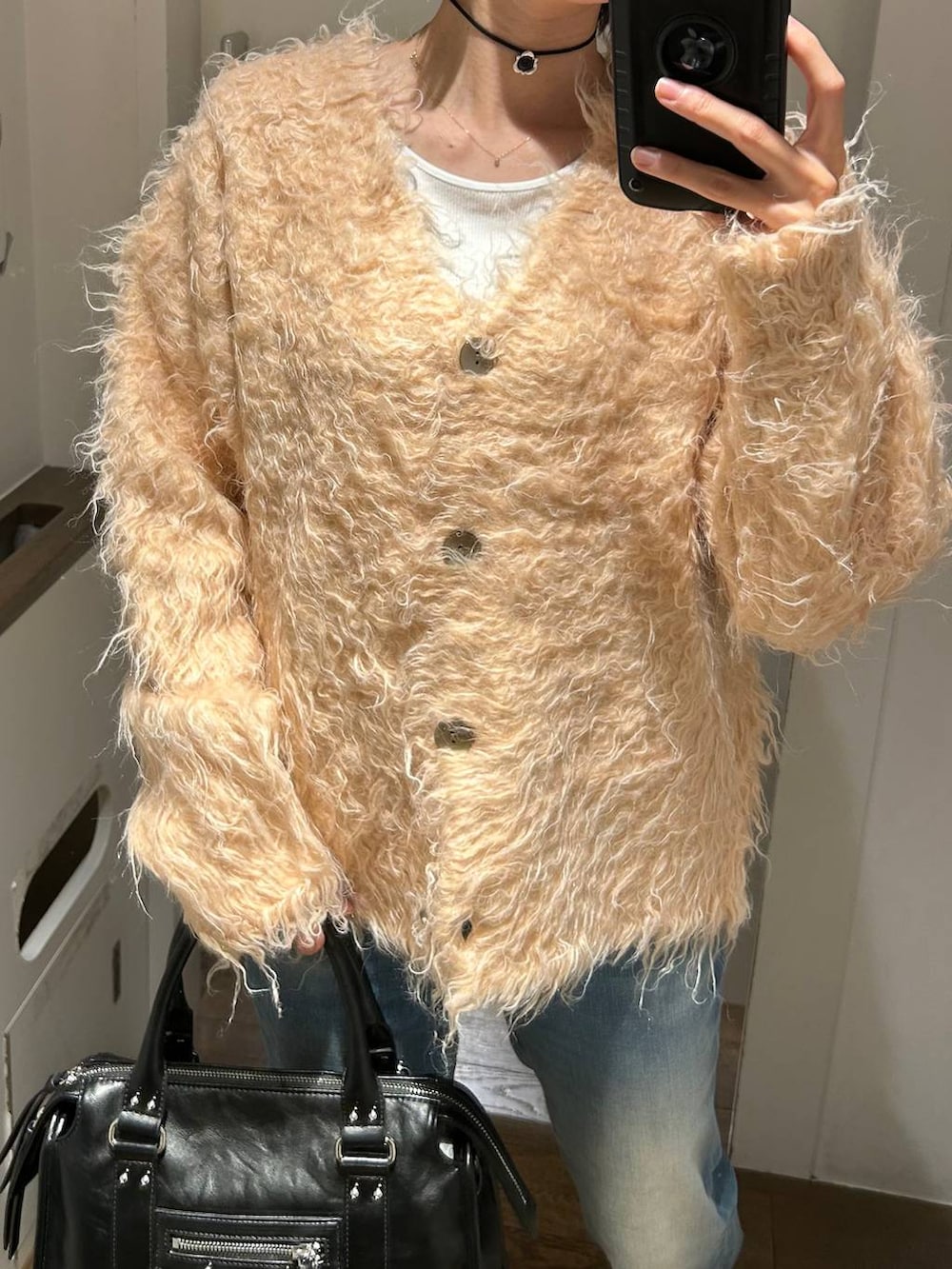 ブラック系のボストンバッグ、ブルー系のデニムパンツ、オレンジ系のカーディガン/ボレロを着用したレディースの冬コーディネートの3枚目の写真