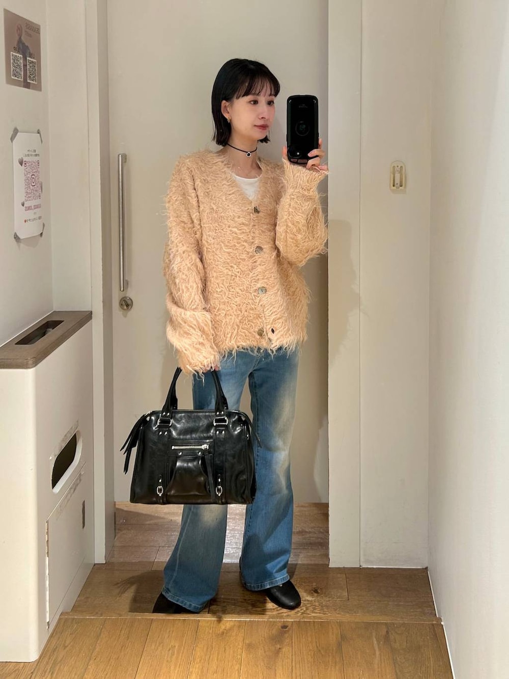 ブラック系のボストンバッグ、ブルー系のデニムパンツ、オレンジ系のカーディガン/ボレロを着用したレディースの冬コーディネートの2枚目の写真