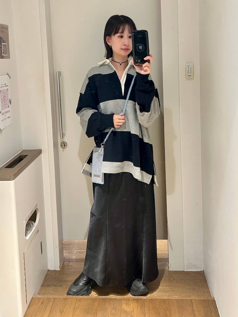 ブラック系のブーツ、グレー系のポロシャツ、ブラック系のスカートを着用したレディースの冬コーディネートの2枚目の写真