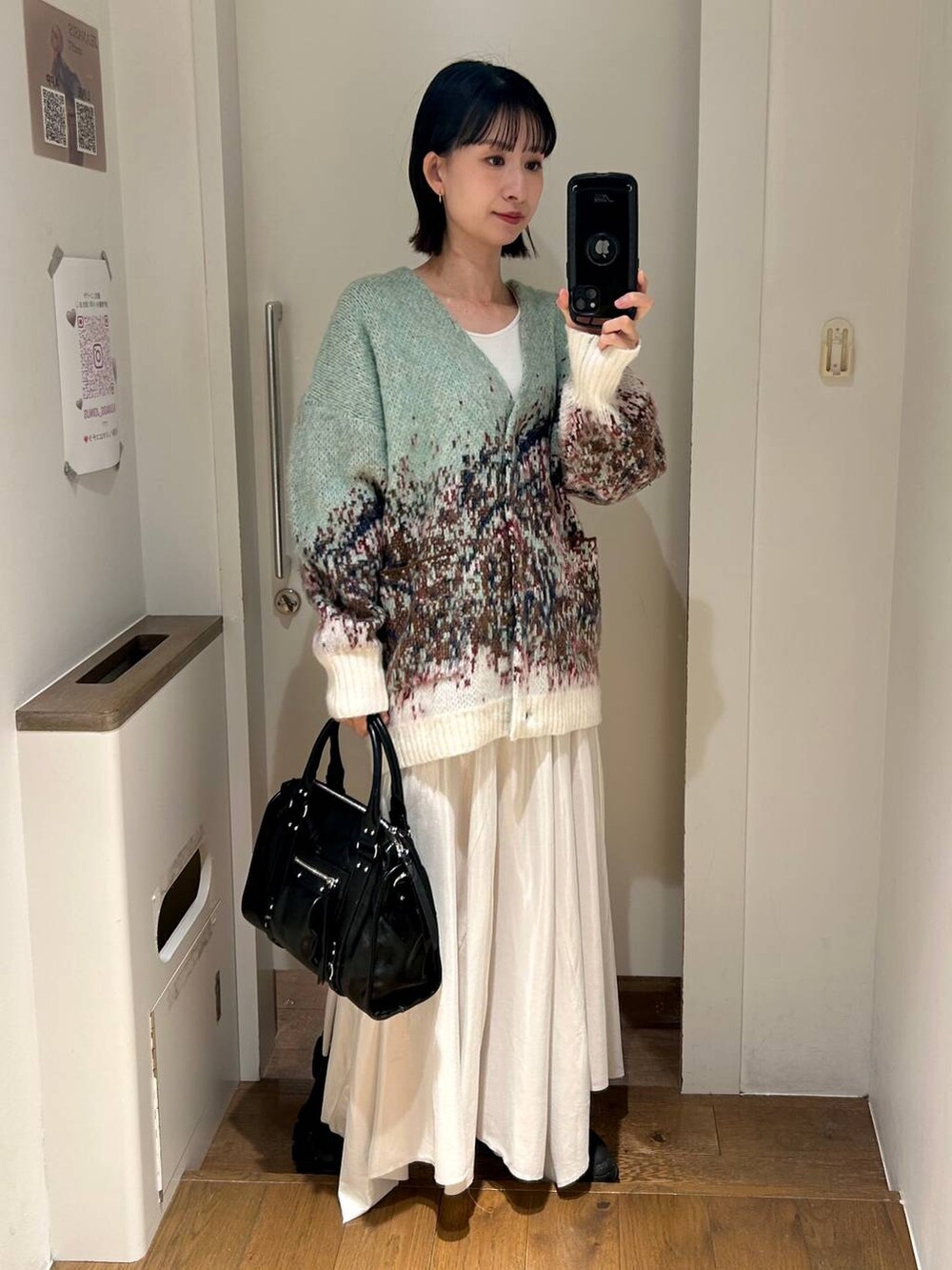 ブラック系のトートバッグ、ブラック系のブーツ、ホワイト系のスカートを着用したレディースの秋コーディネートの2枚目の写真