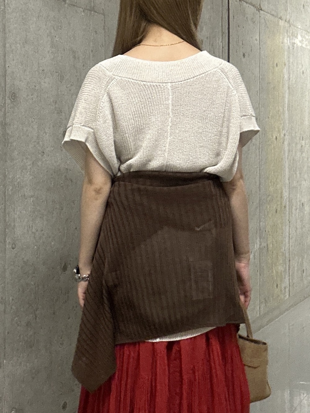ブラウン系のカーディガン/ボレロ、ホワイト系のニット/セーター、レッド系のスカートを着用したレディースの夏コーディネートの6枚目の写真