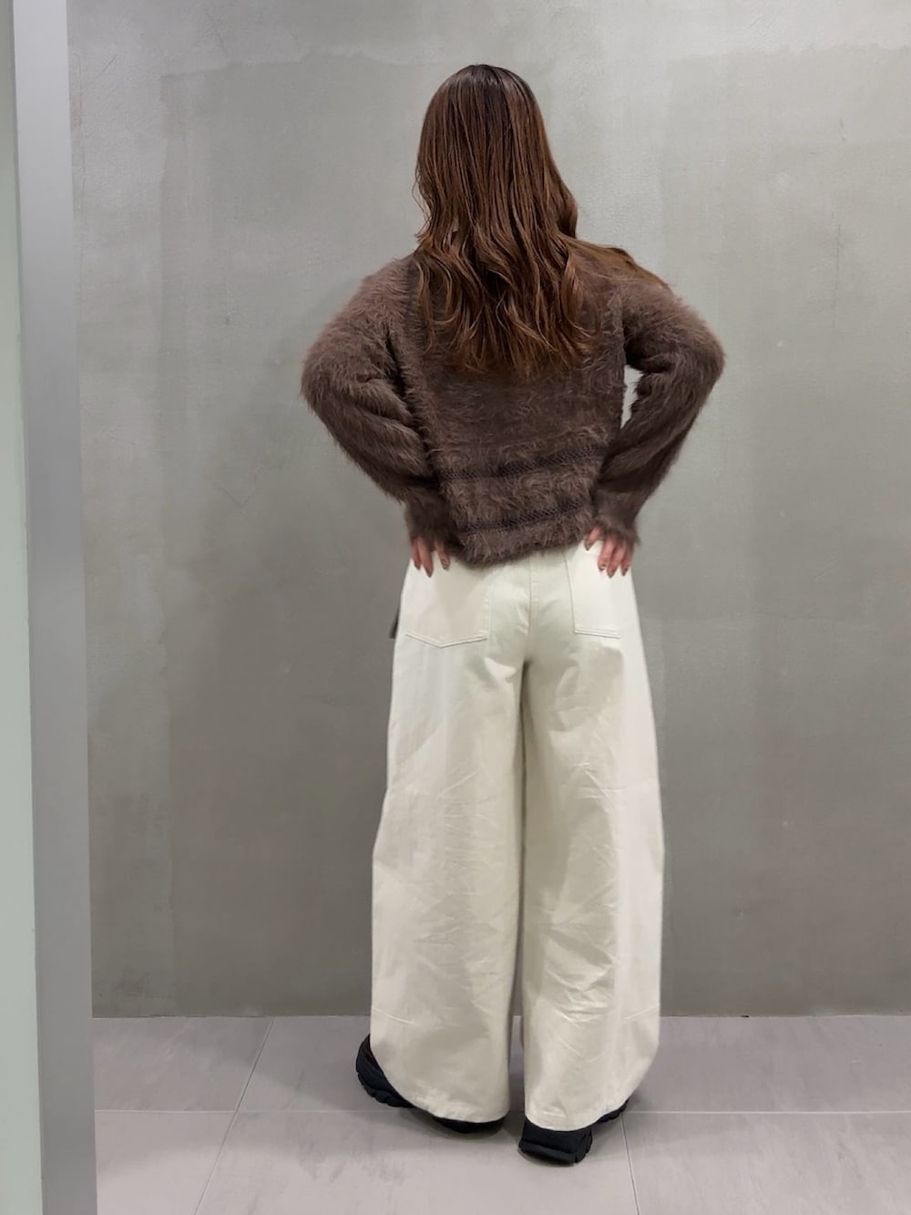 ブラウン系のニット/セーター、ホワイト系のその他パンツ、ブラウン系のスニーカーを着用したレディースの秋コーディネートの3枚目の写真