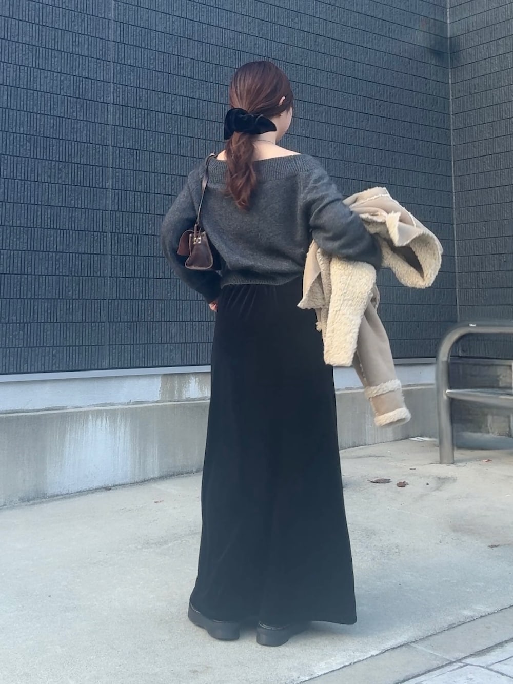 グレー系のニット/セーター、ブラック系のスカート、ブラック系のヘアゴムを着用したレディースの冬コーディネートの3枚目の写真