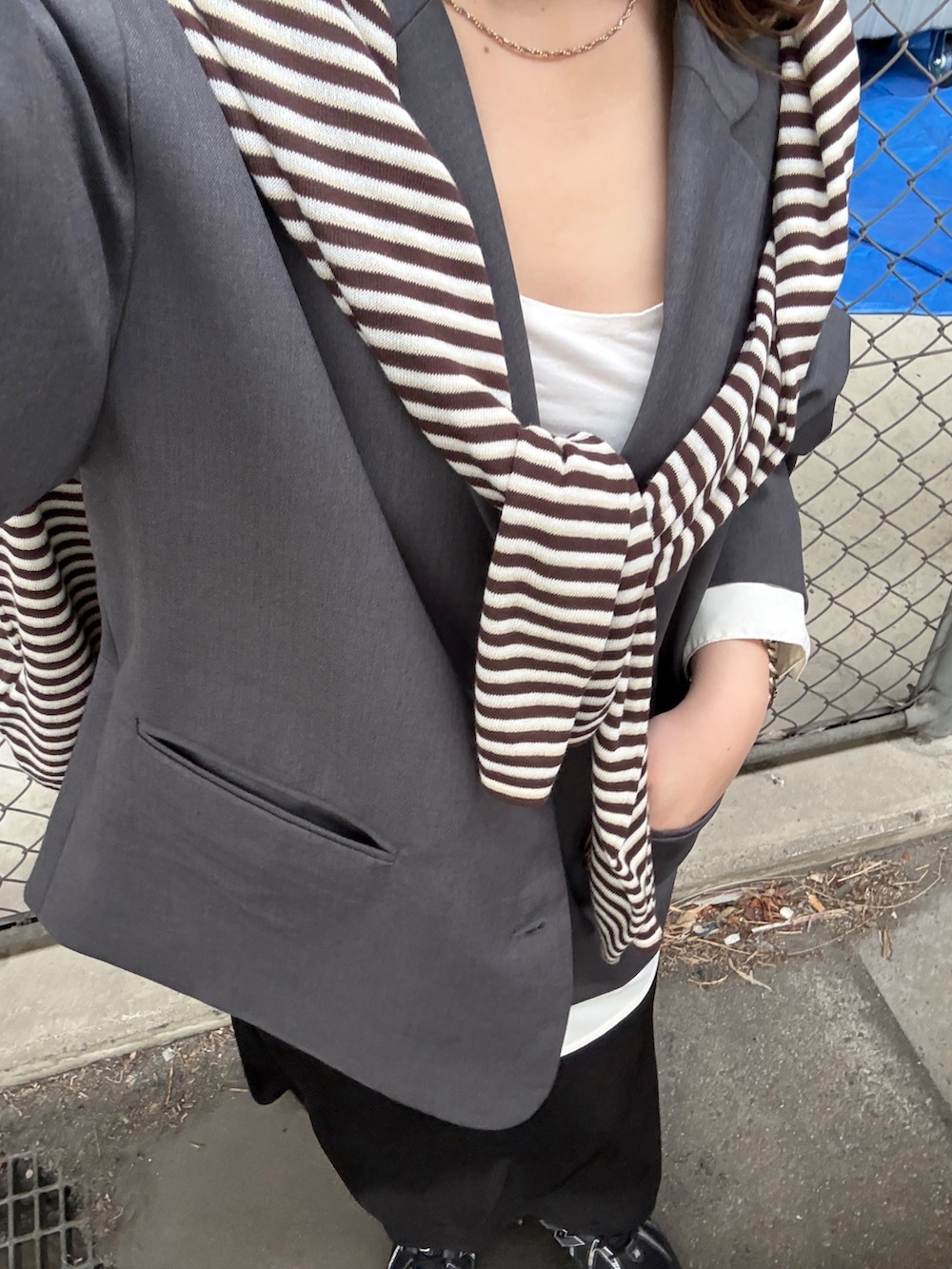 ブラウン系のニット/セーター、グレー系のその他アウター、ブラック系のスカートを着用したレディースの春コーディネートの4枚目の写真