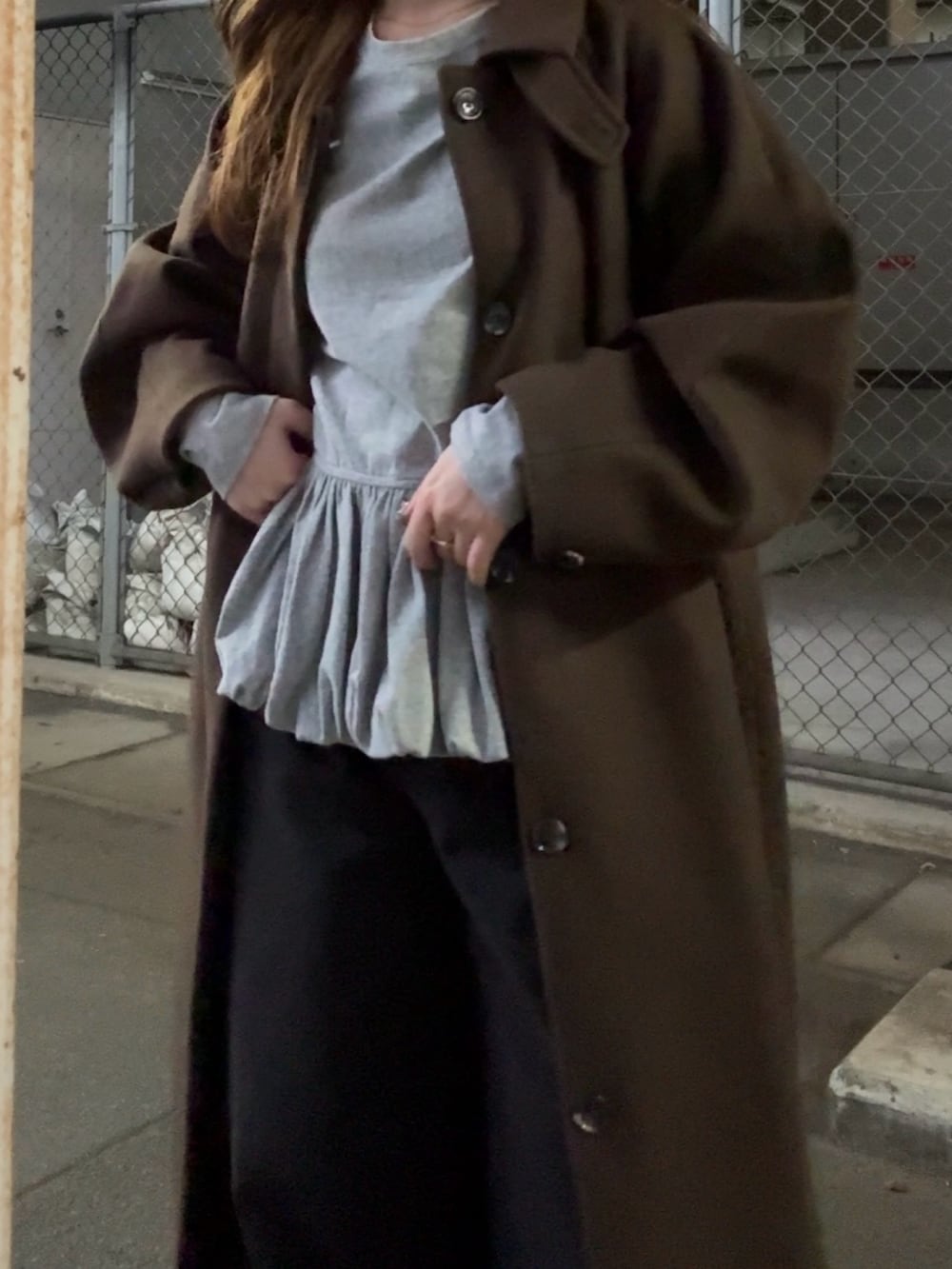 ブラウン系のステンカラーコート、グリーン系のTシャツ/カットソー、ブラック系のデニムパンツを着用したレディースの秋コーディネートの5枚目の写真