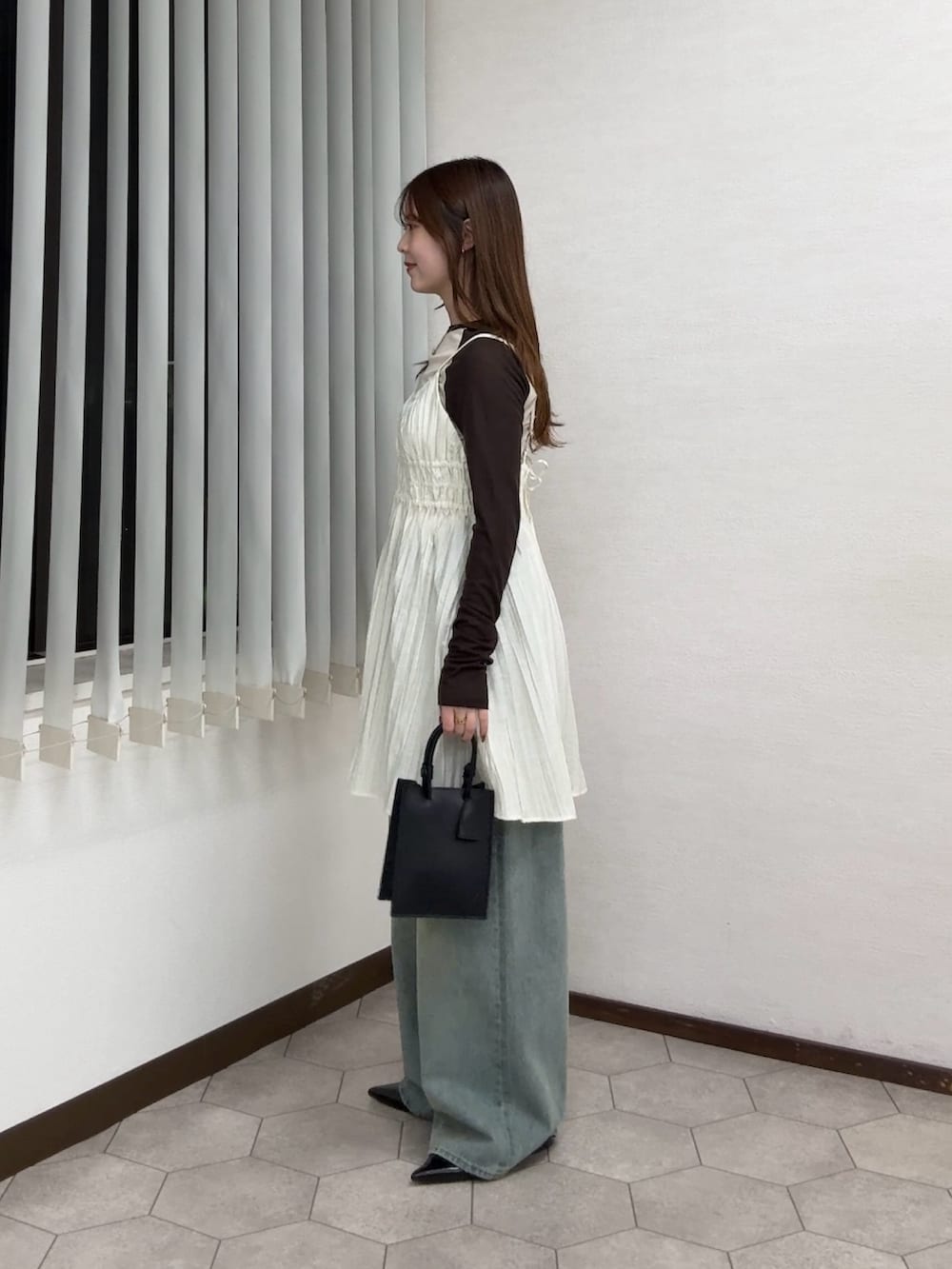 ホワイト系のワンピース、ベージュ系のTシャツ/カットソー、ブルー系のデニムパンツを着用したレディースの春コーディネートの2枚目の写真