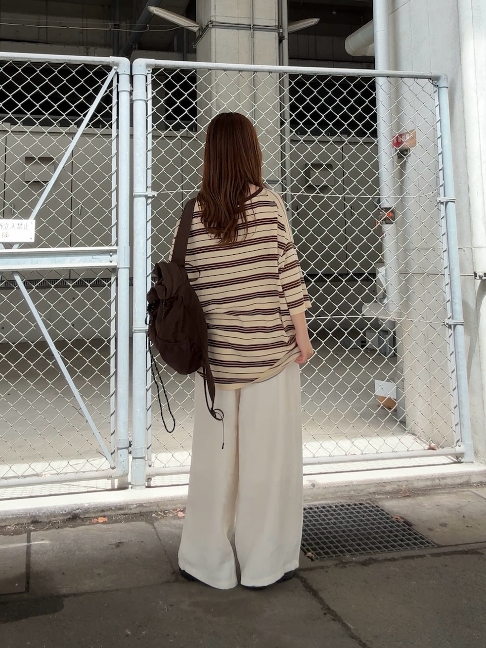 イエロー系のニット/セーター、ホワイト系のその他パンツ、ブラウン系のバックパック/リュックを着用したレディースの春コーディネートの3枚目の写真