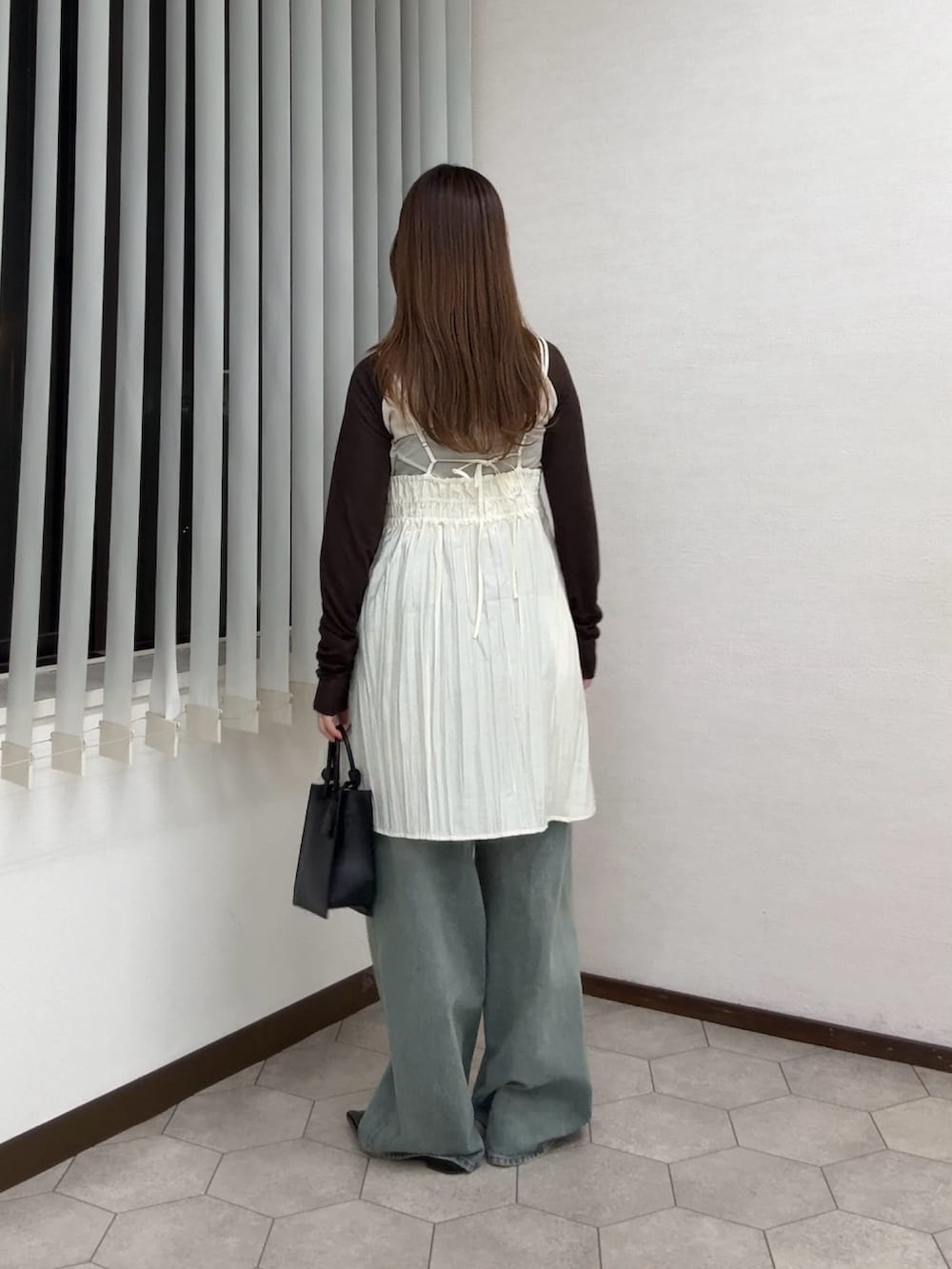 ホワイト系のワンピース、ベージュ系のTシャツ/カットソー、ブルー系のデニムパンツを着用したレディースの春コーディネートの3枚目の写真