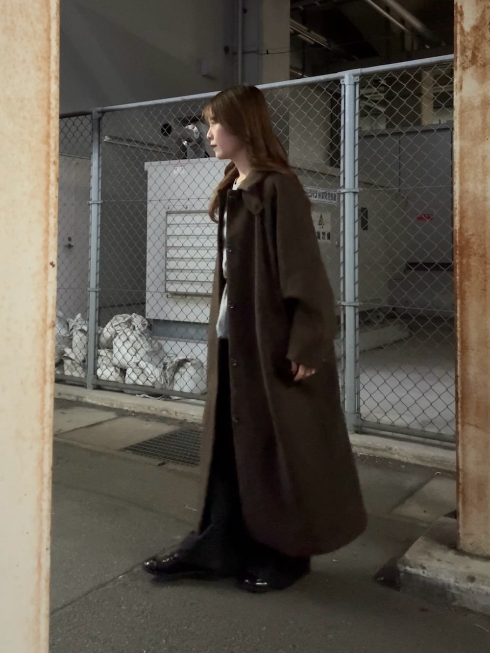 ブラウン系のステンカラーコート、グリーン系のTシャツ/カットソー、ブラック系のデニムパンツを着用したレディースの秋コーディネートの3枚目の写真