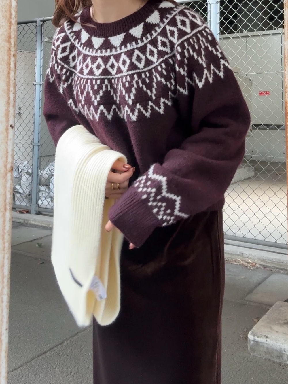 レッド系のニット/セーター、ブラウン系のスカート、ホワイト系のマフラーを着用したレディースの冬コーディネートの5枚目の写真