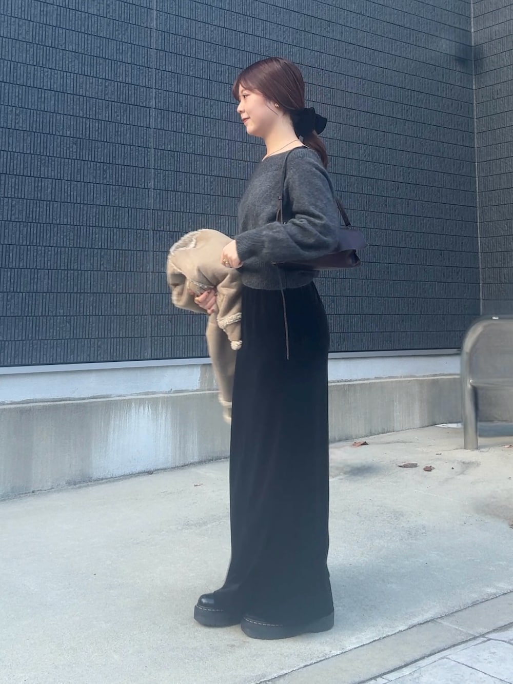 グレー系のニット/セーター、ブラック系のスカート、ブラック系のヘアゴムを着用したレディースの冬コーディネートの2枚目の写真