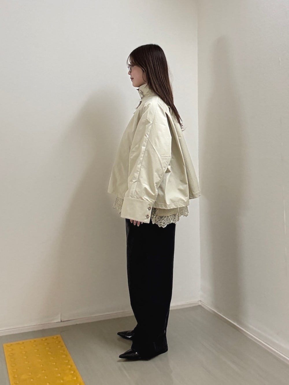 グレー系のステンカラーコート、ベージュ系のキャミソール、ブラック系のデニムパンツを着用したレディースの冬コーディネートの2枚目の写真