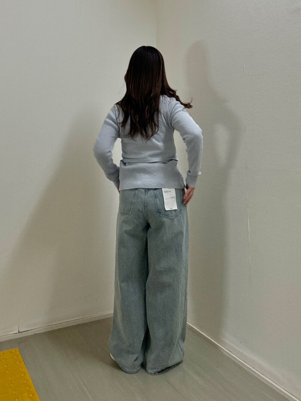 ブルー系のニット/セーター、ブルー系のデニムパンツ、ホワイト系のパンプスを着用したレディースの冬コーディネートの3枚目の写真