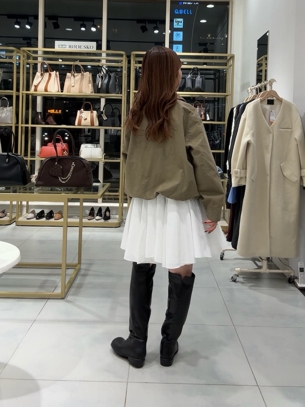 グリーン系のブルゾン、ホワイト系のワンピース、ブラック系のブーツを着用したレディースの冬コーディネートの3枚目の写真