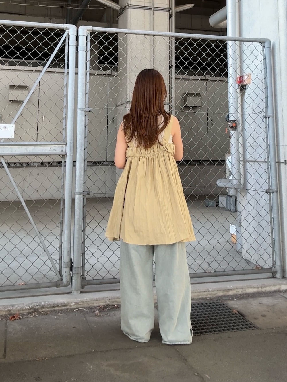 ベージュ系のタンクトップ、ブルー系のデニムパンツ、ベージュ系のワンピースを着用したレディースの春コーディネートの3枚目の写真