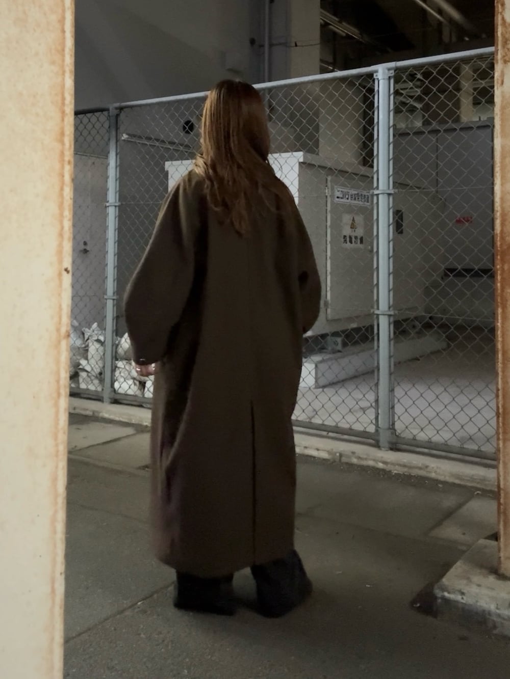 ブラウン系のステンカラーコート、グリーン系のTシャツ/カットソー、ブラック系のデニムパンツを着用したレディースの秋コーディネートの4枚目の写真