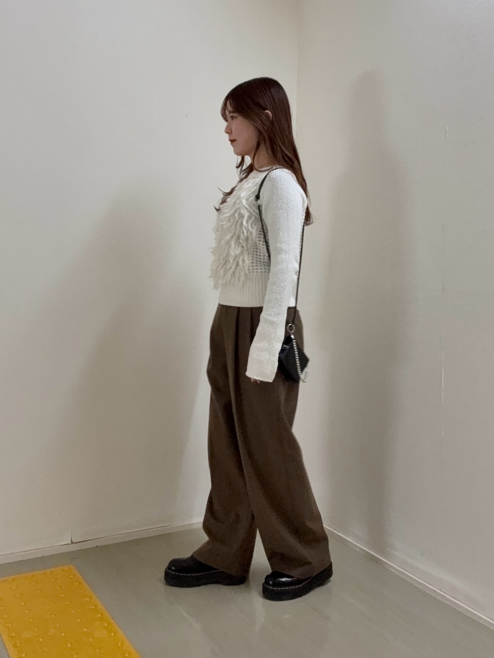 ホワイト系のニット/セーター、ブラウン系のその他パンツ、ブラック系の財布を着用したレディースの冬コーディネートの2枚目の写真