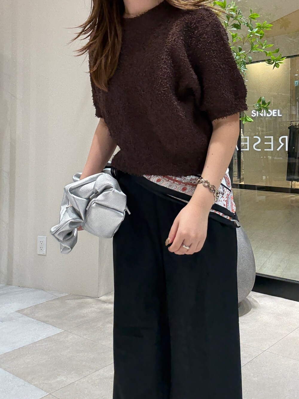 ブラウン系のニット/セーター、ブラック系のスラックス、シルバー系のハンドバッグを着用したレディースの秋コーディネートの3枚目の写真