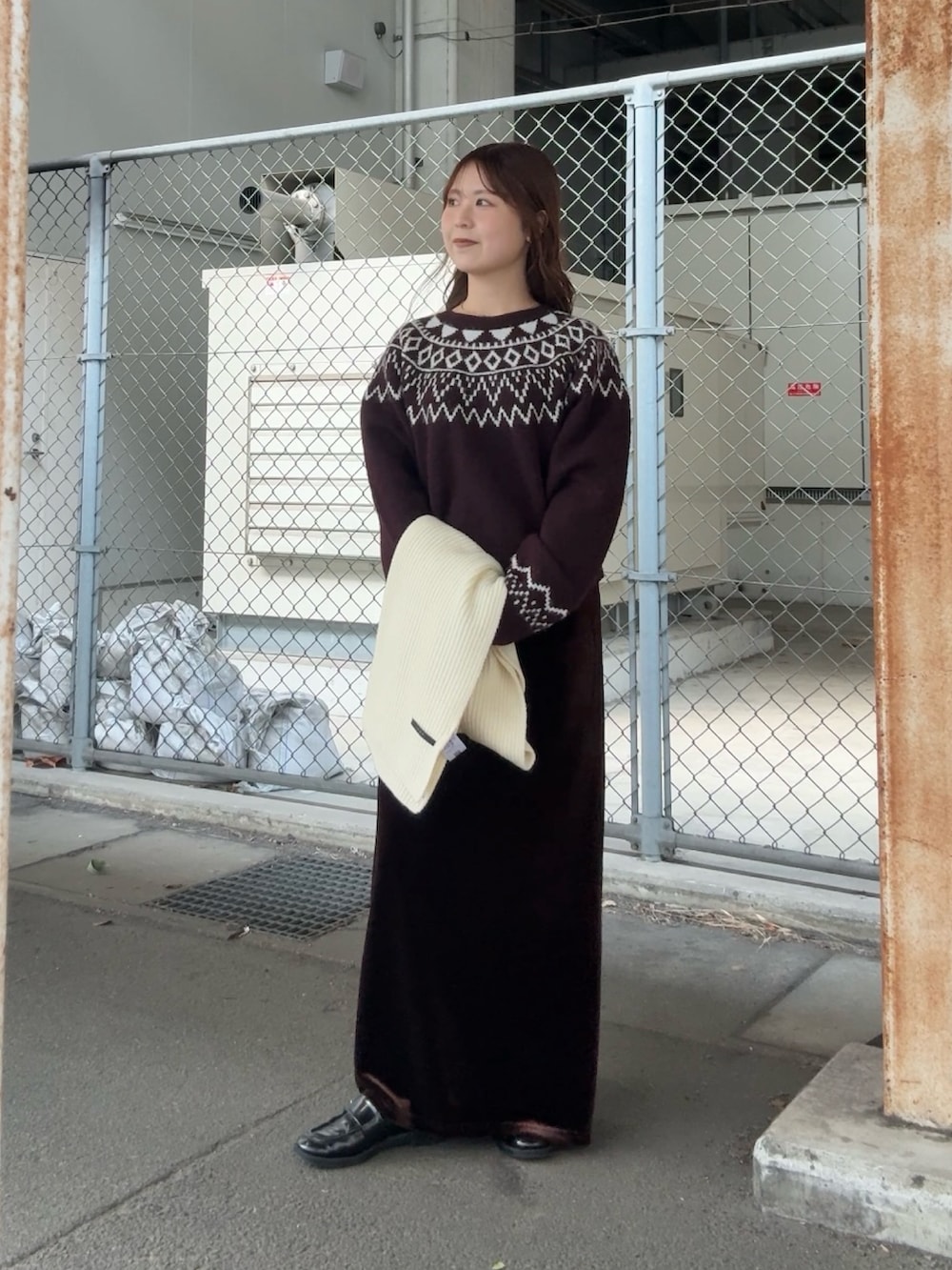 レッド系のニット/セーター、ブラウン系のスカート、ホワイト系のマフラーを着用したレディースの冬コーディネートの2枚目の写真