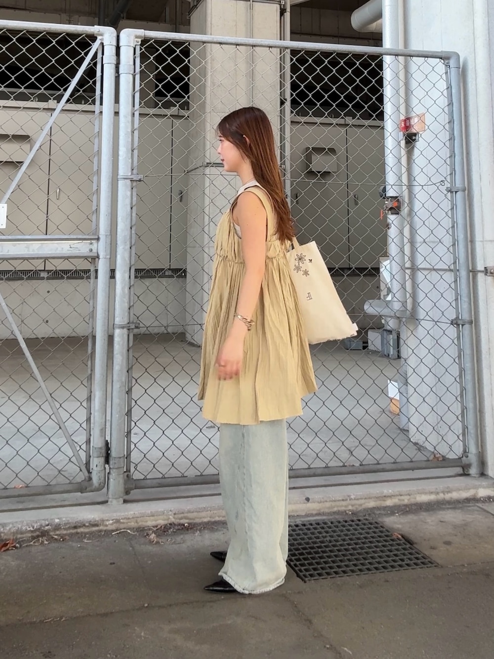 ベージュ系のタンクトップ、ブルー系のデニムパンツ、ベージュ系のワンピースを着用したレディースの春コーディネートの2枚目の写真