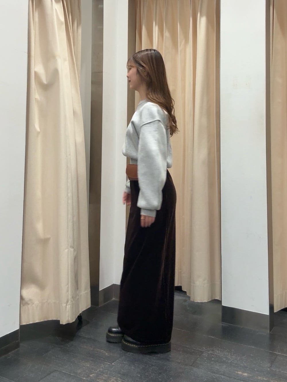 グリーン系のニット/セーター、ブラウン系のスカート、ブラウン系のベルトを着用したレディースの冬コーディネートの2枚目の写真