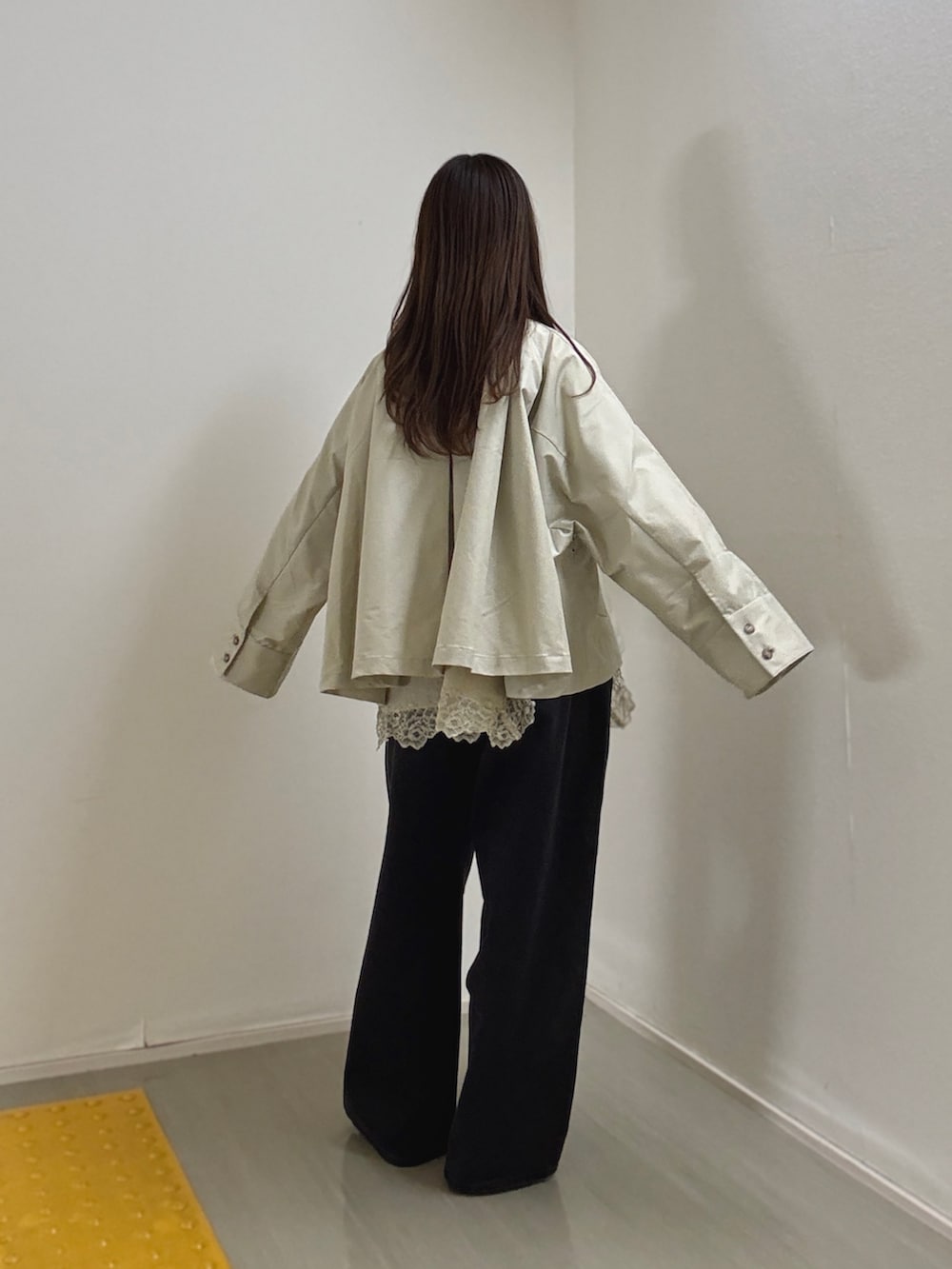 グレー系のステンカラーコート、ベージュ系のキャミソール、ブラック系のデニムパンツを着用したレディースの冬コーディネートの3枚目の写真