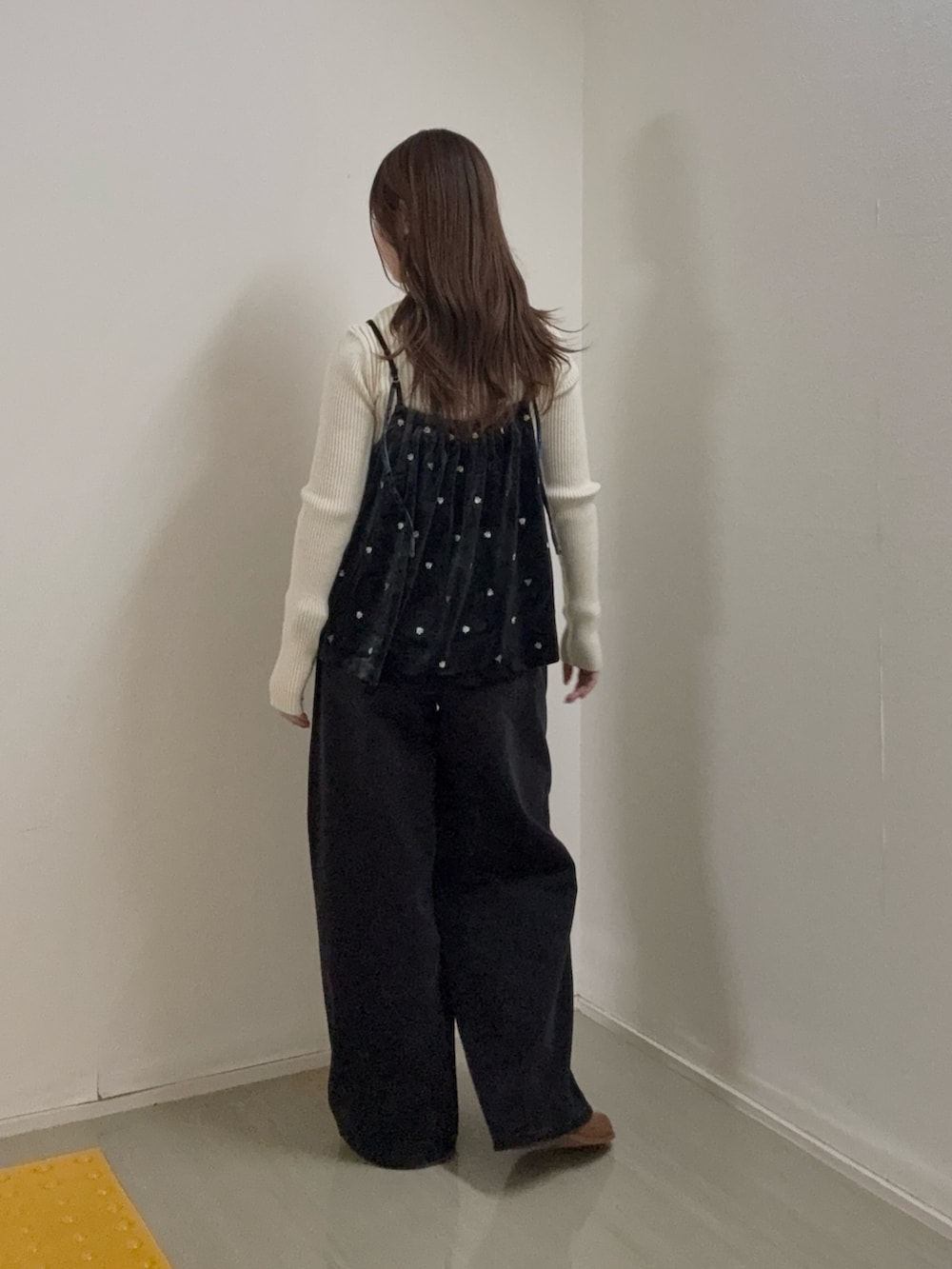 グレー系のキャミソール、ホワイト系のニット/セーター、ブラック系のデニムパンツを着用したレディースの秋コーディネートの3枚目の写真